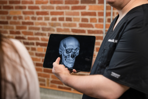 Oral surgeon pointing at TMJ in a patient scan.